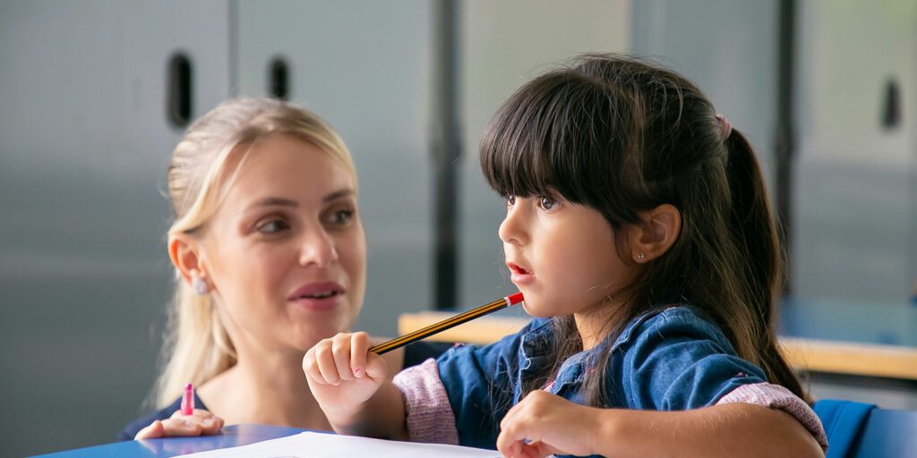 Teacher helping elementary student in a classroom.